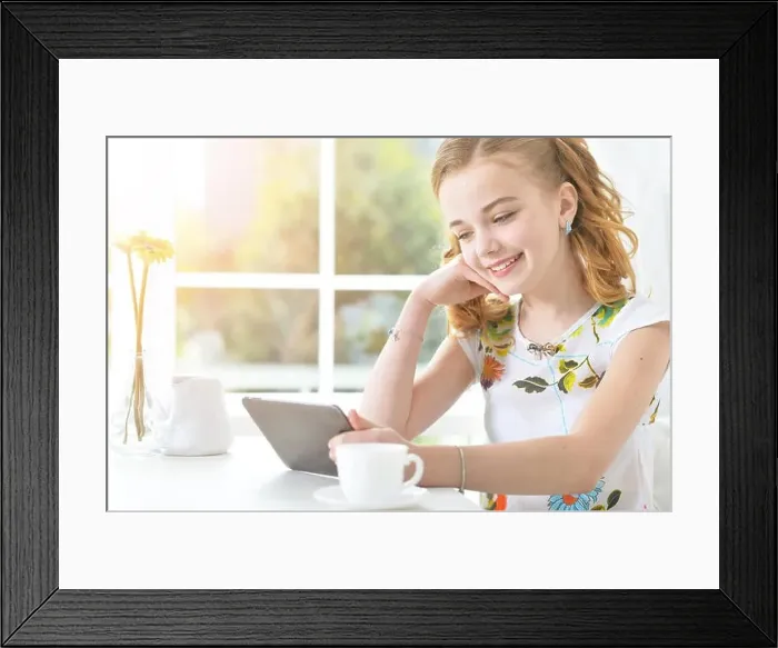 Framed Print : Cute little girl sitting at table and looking at laptop Framed Print : Cute little girl sitting at table and looking at laptop