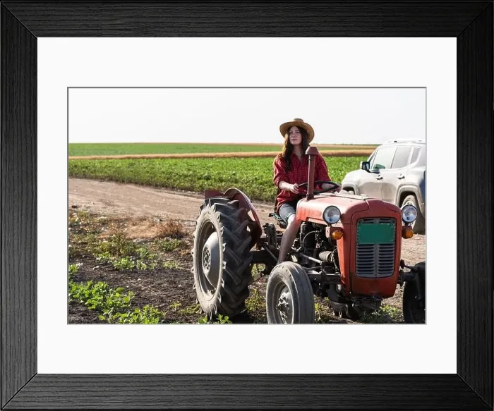 Framed Print : Female farmer driving a tractor in field Framed Print : Female farmer driving a tractor in field