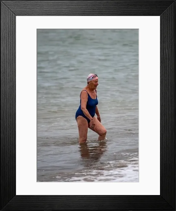 Framed Print : older lady walking out of the sea after wild cold water swimming in the solent Framed Print : older lady walking out of the sea after wild cold water swimming in the solent