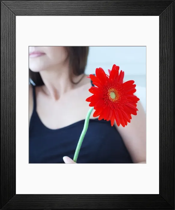 Framed Print : Defocused attractive woman holding red flower Framed Print : Defocused attractive woman holding red flower
