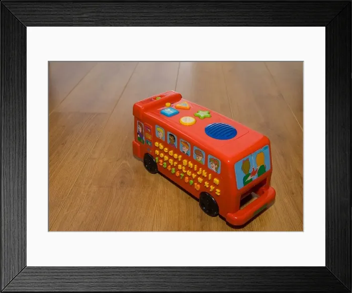 Framed Print : Toy red bus on a wooden laminate floor Framed Print : Toy red bus on a wooden laminate floor