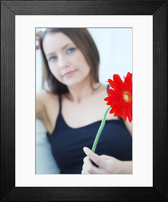 Framed Print : Defocused attractive woman holding a red flower