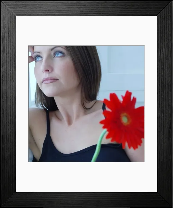 Framed Print : Defocused attractive woman holding a red flower Framed Print : Defocused attractive woman holding a red flower
