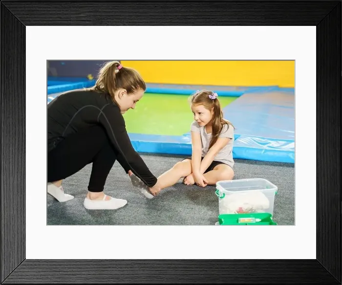 Framed Print : girl having pain in ankle and getting help after jumping on trampoline Framed Print : girl having pain in ankle and getting help after jumping on trampoline