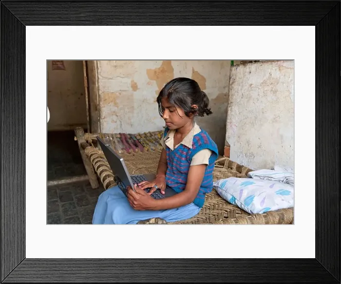 Framed Print : India, uttar Pradesh, Agra Serious pre-teenage girl using laptop whilst sitting on bed Framed Print : India, uttar Pradesh, Agra Serious pre-teenage girl using laptop whilst sitting on bed