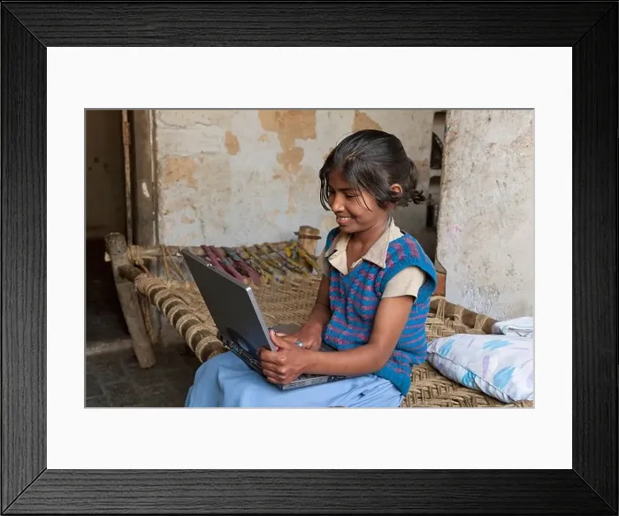 Framed Print : India, uttar Pradesh, Agra, Happy pre-teenage girl using laptop whilst sitting on bed Framed Print : India, uttar Pradesh, Agra, Happy pre-teenage girl using laptop whilst sitting on bed
