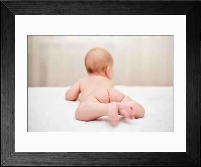 Framed Print : Cute little baby in diaper on bed