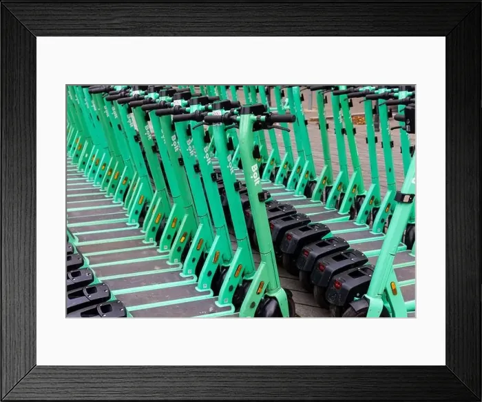 Framed Print : Rows of green electric scooters parked on a city sidewalk. Urban personal transport vehicles for rent Framed Print : Rows of green electric scooters parked on a city sidewalk. Urban personal transport vehicles for rent