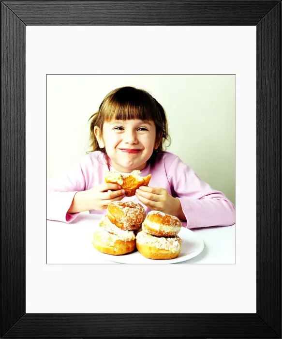 Framed Print : A small girl eating doughnuts Framed Print : A small girl eating doughnuts