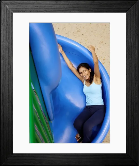 Framed Print : Woman sliding on slide, looking up at camera Framed Print : Woman sliding on slide, looking up at camera