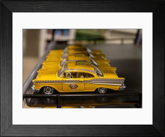 Framed Print : Row of miniature yellow taxi cabs lined up on a shelf - classic New York City Checker Taxi design Framed Print : Row of miniature yellow taxi cabs lined up on a shelf - classic New York City Checker Taxi design