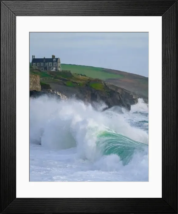 Framed Print : Massive waves pounding into Porthleven beach with Tye Rock Manor perched on the cliff behind Framed Print : Massive waves pounding into Porthleven beach with Tye Rock Manor perched on the cliff behind