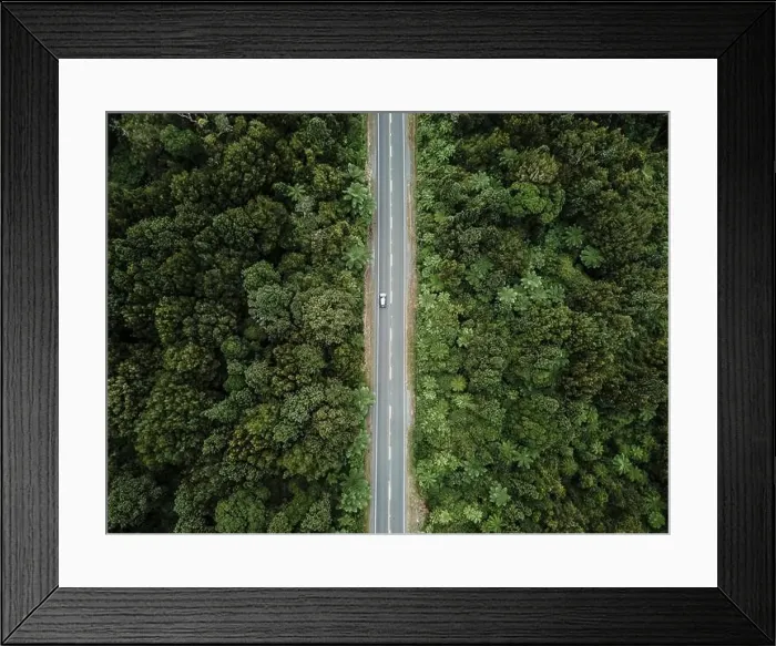 Framed Print : drone view zenithal shot of the straight road with a car going through the dense lush forest next to the green trees Framed Print : drone view zenithal shot of the straight road with a car going through the dense lush forest next to the green trees