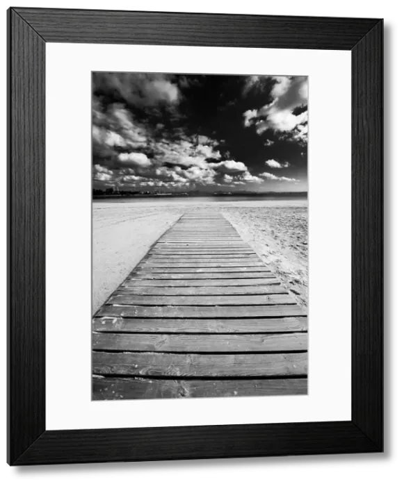 Framed Print : Dramatic view of a wooden boardwalk stretching along a beach towards the sea in Alcudia, Spain Framed Print : Dramatic view of a wooden boardwalk stretching along a beach towards the sea in Alcudia, Spain