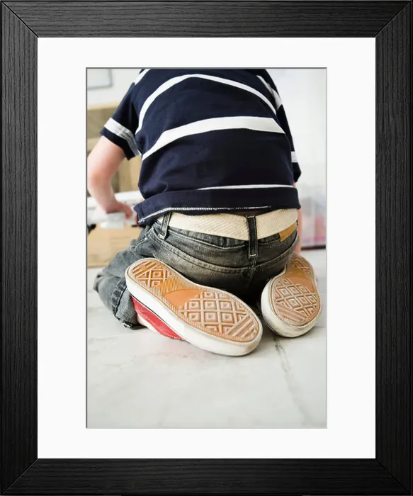 Framed Print : Little boy kneeling on floor, rear view