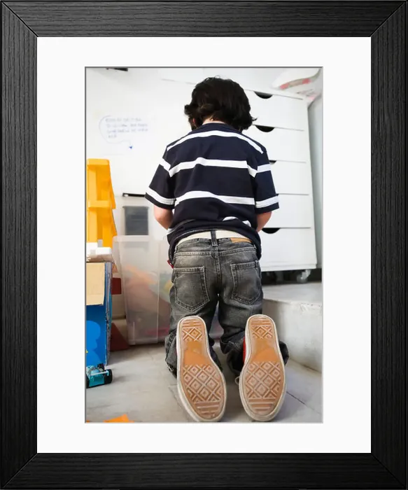 Framed Print : Little boy kneeling on floor in front of plastic bin, rear view Framed Print : Little boy kneeling on floor in front of plastic bin, rear view