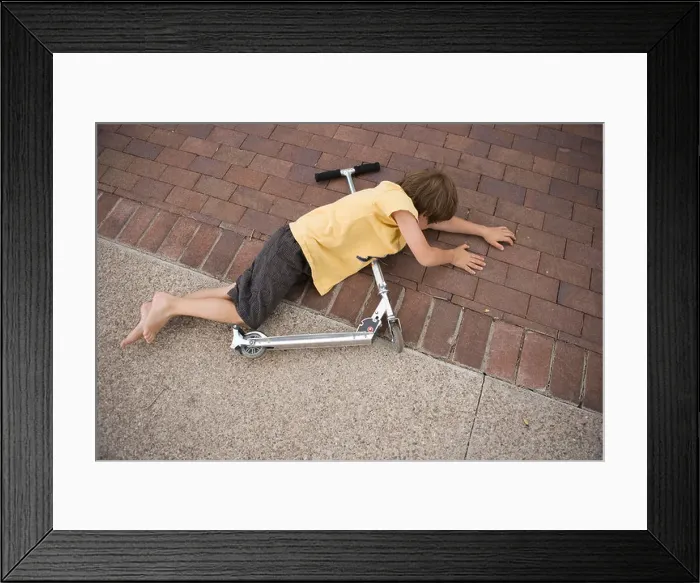Framed Print : seven year old boy falls off his scooter and lands on the driveway Framed Print : seven year old boy falls off his scooter and lands on the driveway