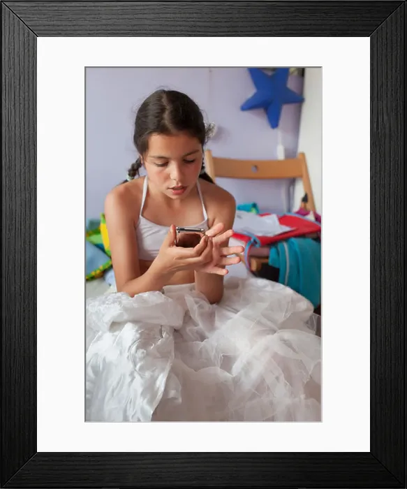 Framed Print : Adolescent girl checks social network site on mobile device Framed Print : Adolescent girl checks social network site on mobile device