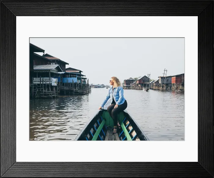 Framed Print : Caucasian blonde woman in denim shirt having a boat ride along floating houses on Inle lake, Myanmar