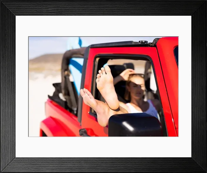 Framed Print : Young Caucasian woman relaxes in a red jeep on a road trip Framed Print : Young Caucasian woman relaxes in a red jeep on a road trip
