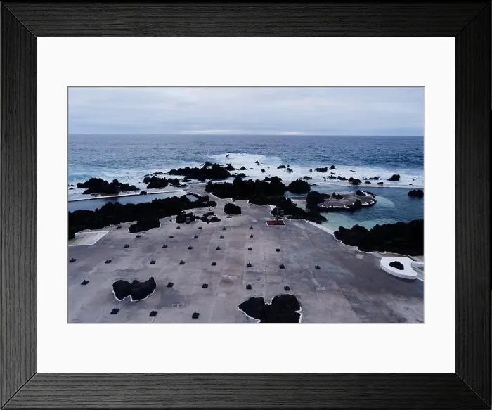 Framed Print : Empty parasol stands on concrete with volcanic rock and crashing waves at Porto Moniz natural pools Framed Print : Empty parasol stands on concrete with volcanic rock and crashing waves at Porto Moniz natural pools