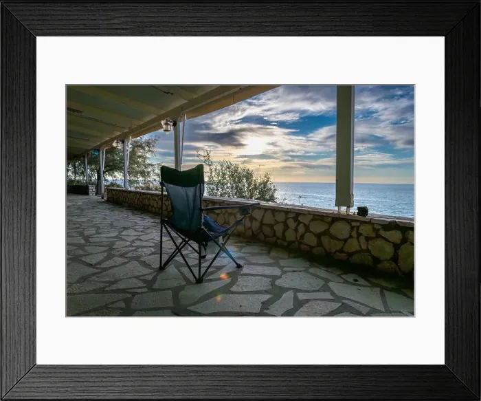 Framed Print : A folding chair on the covered patio of a seaside building with a great view of the sea and sunset sky clouds Framed Print : A folding chair on the covered patio of a seaside building with a great view of the sea and sunset sky clouds