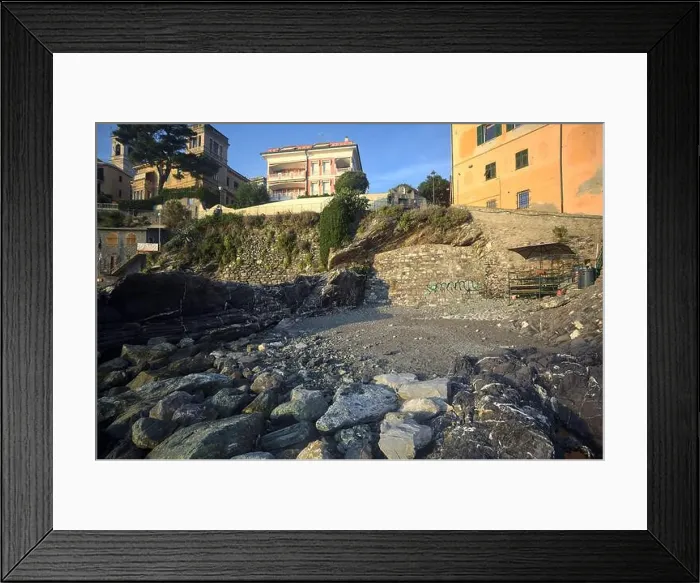 Framed Print : Town buildings on a cliff facing the sea at sunset seen from a cove Framed Print : Town buildings on a cliff facing the sea at sunset seen from a cove