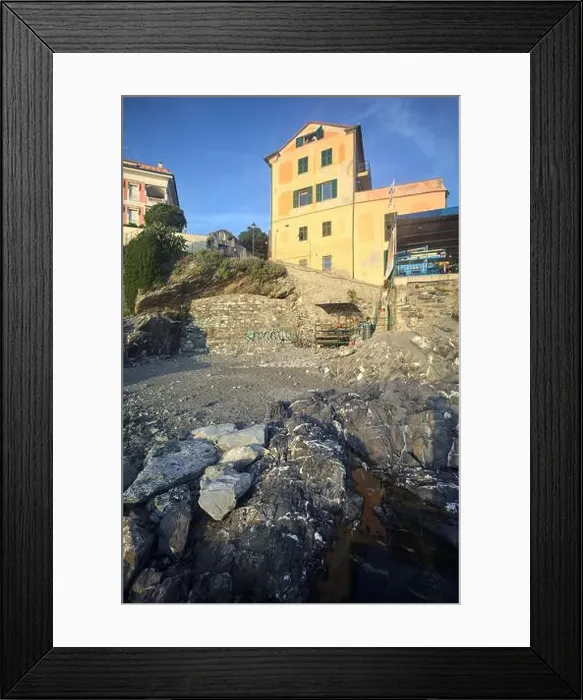 Framed Print : Town buildings on a cliff facing the sea at sunset seen from a cove Framed Print : Town buildings on a cliff facing the sea at sunset seen from a cove