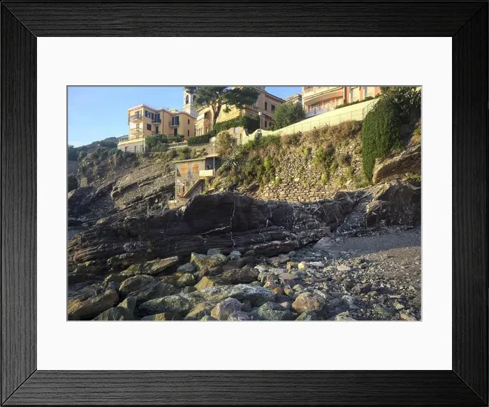 Framed Print : Town buildings on a cliff facing the sea at sunset seen from a cove