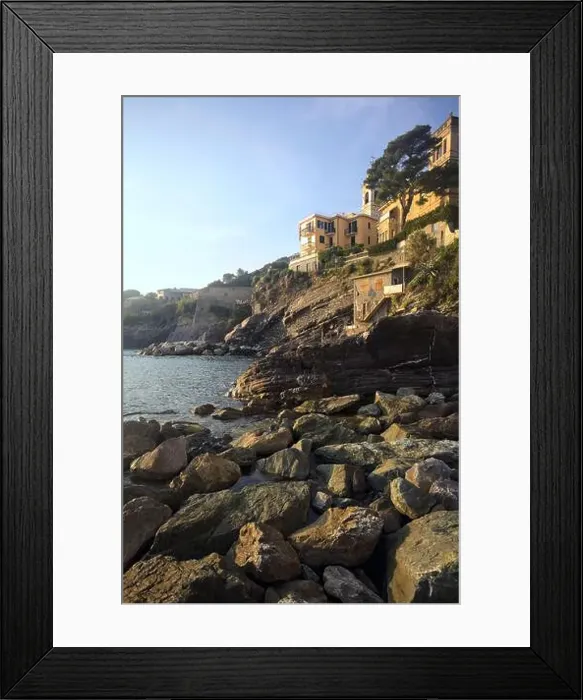 Framed Print : Town buildings on a cliff facing the sea at sunset seen from a cove Framed Print : Town buildings on a cliff facing the sea at sunset seen from a cove