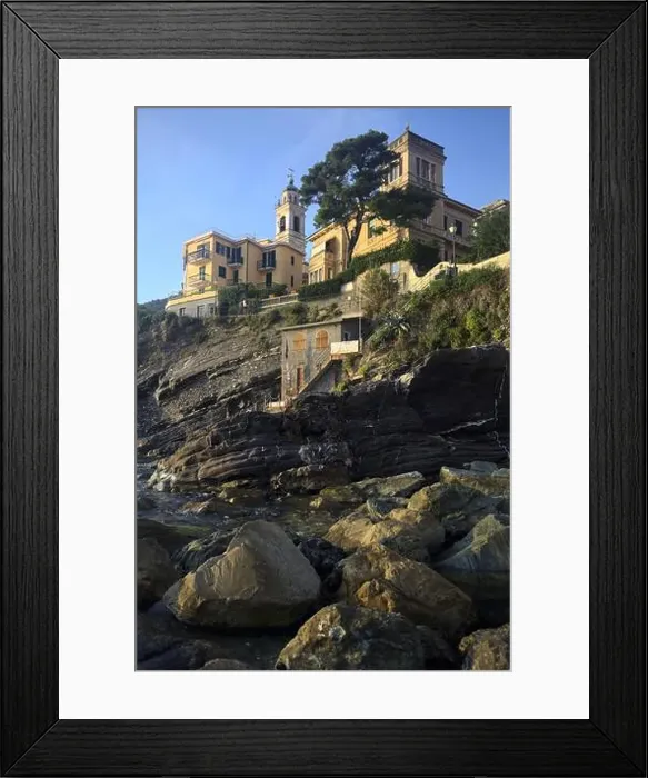 Framed Print : Town buildings on a cliff facing the sea at sunset seen from a cove Framed Print : Town buildings on a cliff facing the sea at sunset seen from a cove