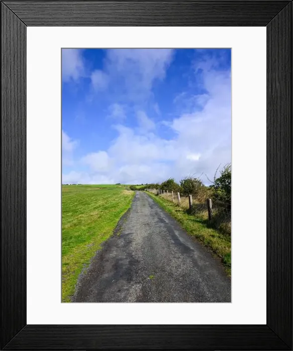 Framed Print : Country road crossing hill country with fence green farmland and blue sky along England Wales border in Shropshire hills Framed Print : Country road crossing hill country with fence green farmland and blue sky along England Wales border in Shropshire hills
