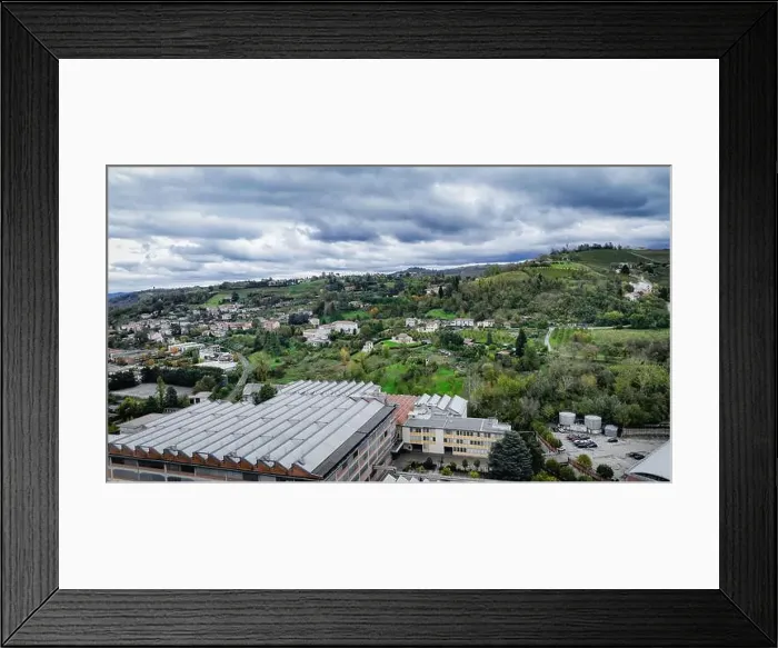 Framed Print : A panoramic view of Alba, Italy features rolling green hills interspersed with residential buildings and rural areas
