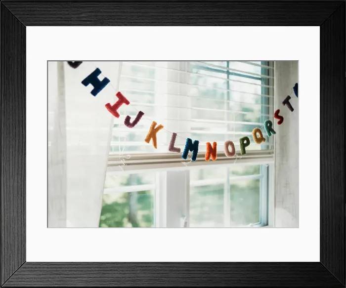 Framed Print : Multi colored alphabet decoration hanging on string by window at home Framed Print : Multi colored alphabet decoration hanging on string by window at home