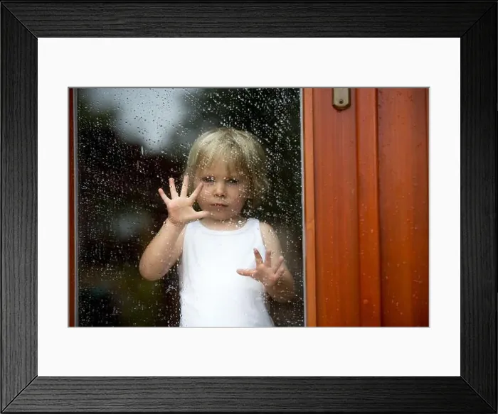 Framed Print : Sad child behind the window on a rainy day Framed Print : Sad child behind the window on a rainy day