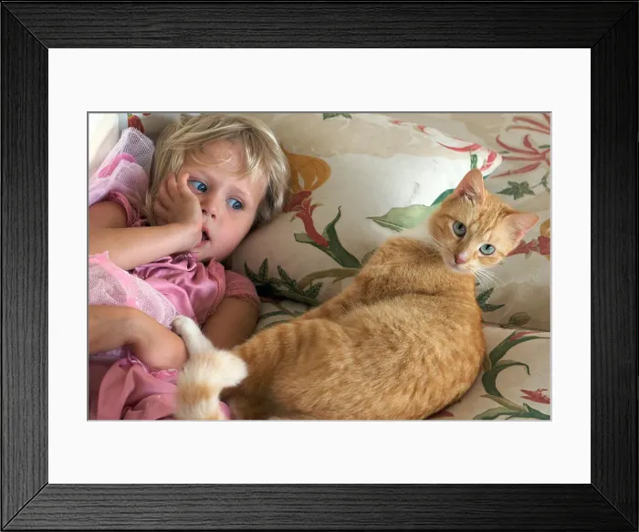 Framed Print : Four year old girl on the couch with her cat Framed Print : Four year old girl on the couch with her cat