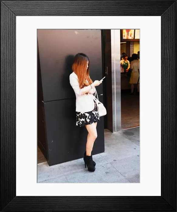 Framed Print : Young Japanese (Asian) girl standing alone & fingering (typing) smart phone on the street Framed Print : Young Japanese (Asian) girl standing alone & fingering (typing) smart phone on the street