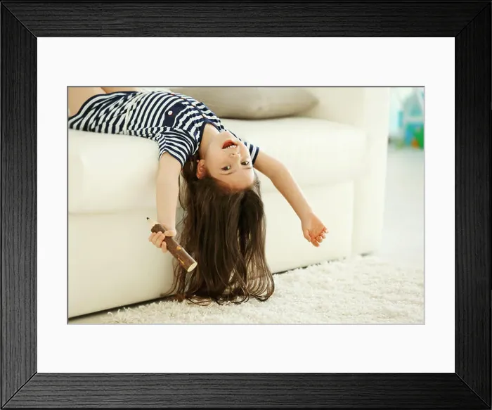 Framed Print : Cute little girl sings in an imagine microphone lying on sofa in the modern room Framed Print : Cute little girl sings in an imagine microphone lying on sofa in the modern room