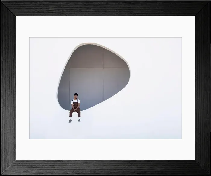 Framed Print : Young man wearing bib overalls sitting on hole in wall Framed Print : Young man wearing bib overalls sitting on hole in wall