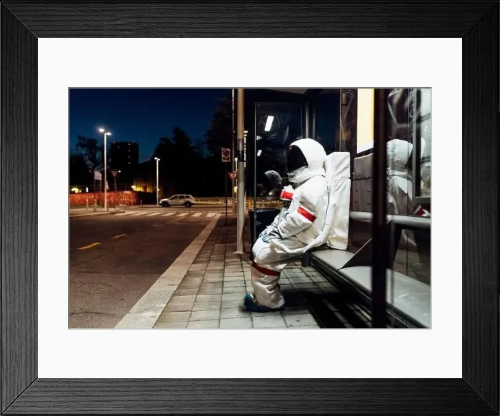 Framed Print : Young female astronaut in space suit waiting at bus stop during night