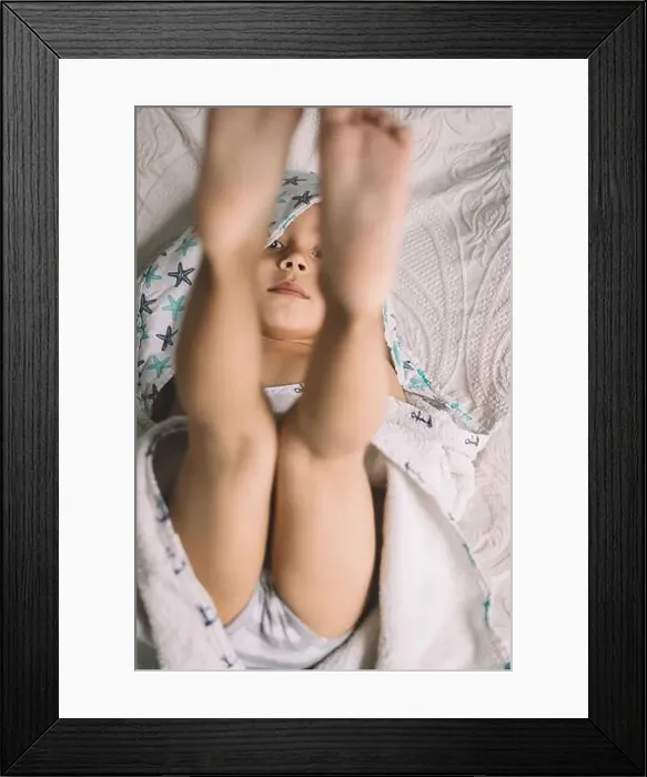 Framed Print : top view of adorable boy lying on bed with legs up and looking at camera Framed Print : top view of adorable boy lying on bed with legs up and looking at camera