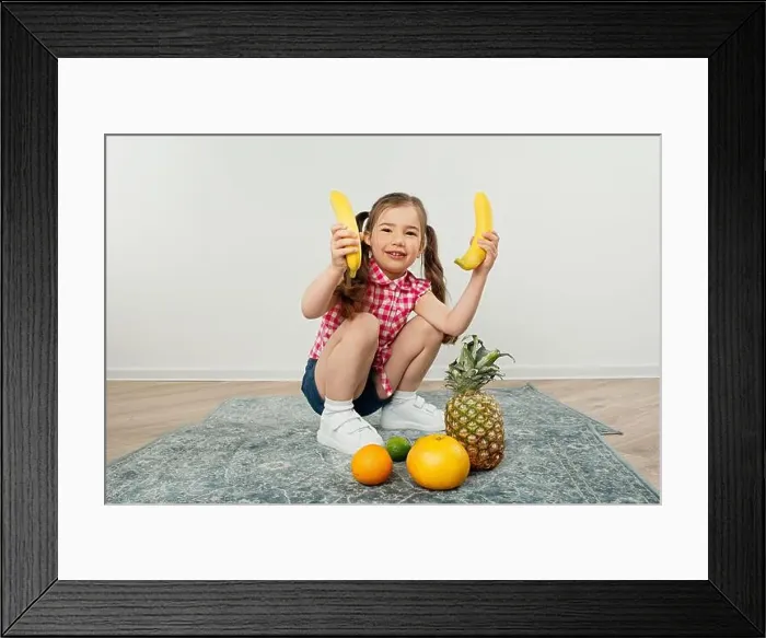 Framed Print : cute kid girl holding bananas in hand, playing with fruits Framed Print : cute kid girl holding bananas in hand, playing with fruits