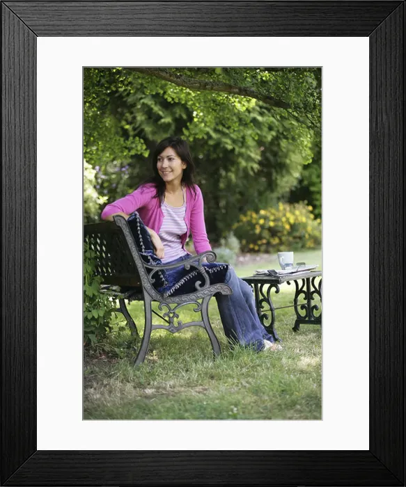 Framed Print : A dark haired woman sitting on a garden bench smiling Framed Print : A dark haired woman sitting on a garden bench smiling