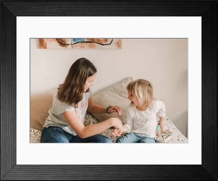 Framed Print : Teenage girl tickling little sister on bed Framed Print : Teenage girl tickling little sister on bed