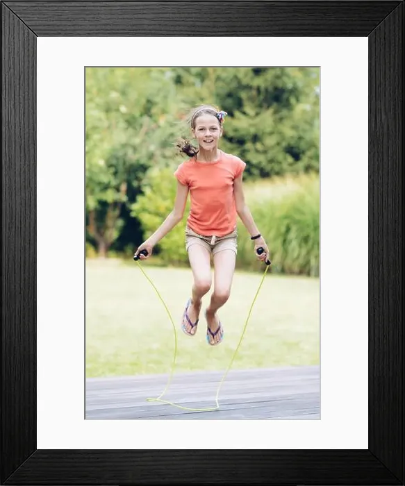 Framed Print : Laughing teenage girl jumping rope in the garden on the terrace in summer Framed Print : Laughing teenage girl jumping rope in the garden on the terrace in summer