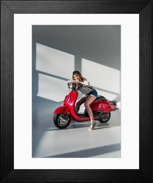 Framed Print : stylish woman in shorts looking at camera while sitting on red scooter