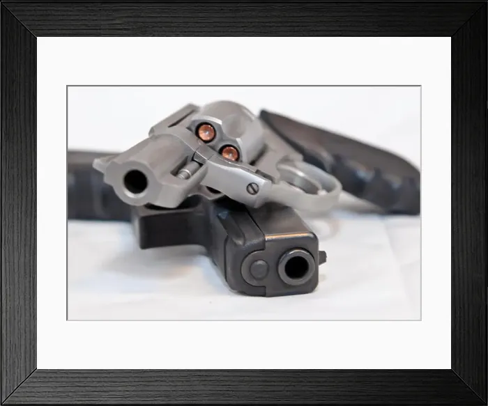 Framed Print : Two handguns, a silver 357 magnum revolver on top of a black 9mm pistol on a white background Framed Print : Two handguns, a silver 357 magnum revolver on top of a black 9mm pistol on a white background