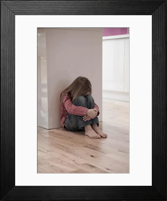 Framed Print : Young girl sat unhappy on the floor Framed Print : Young girl sat unhappy on the floor