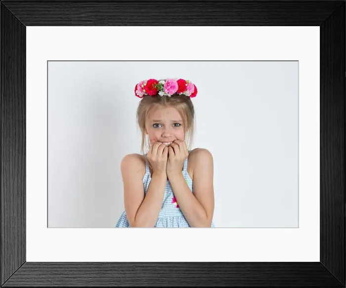 Framed Print : Closeup portrait young little girl biting her finger nails Framed Print : Closeup portrait young little girl biting her finger nails