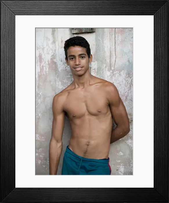 Framed Print : An adolescent Cuban guy leans against a pastel colored wall in Baracoa Framed Print : An adolescent Cuban guy leans against a pastel colored wall in Baracoa
